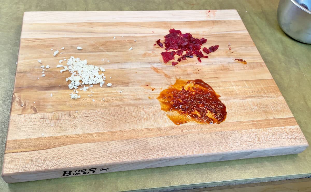 Beets chipotle peppers and garlic on a wood cutting board