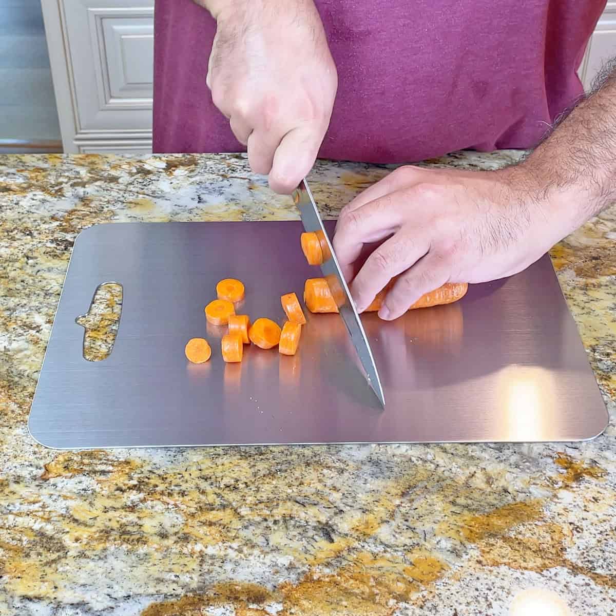 Cutting carrots on a stainless steel cutting board