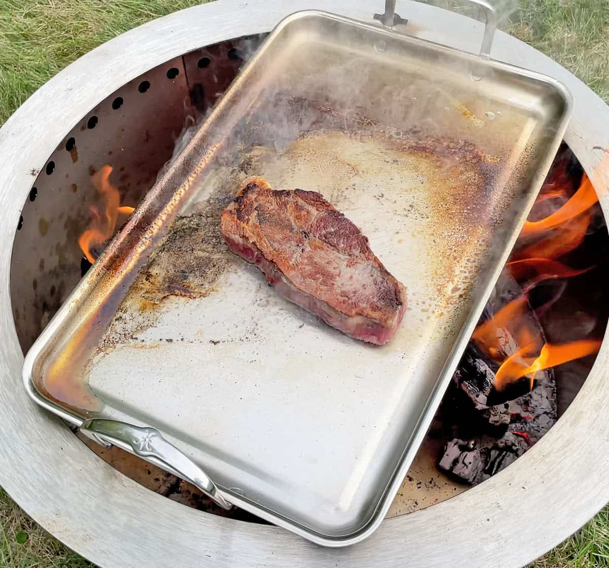 Hestan griddle getting scortched and oil burning into the steel while cooking over an open flame