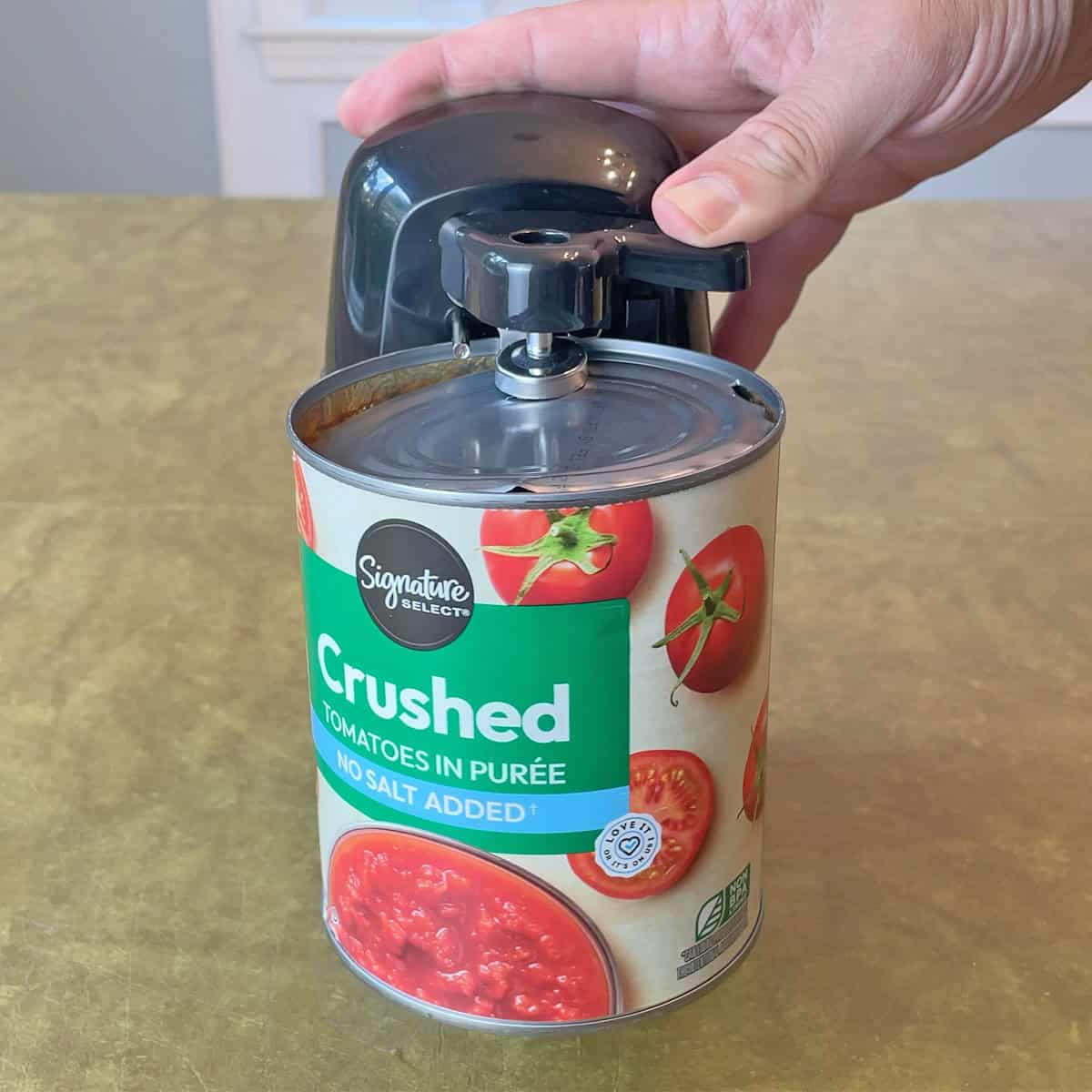 Opening a can with the Amazon Basics 3-in-1 Electric Can Opener