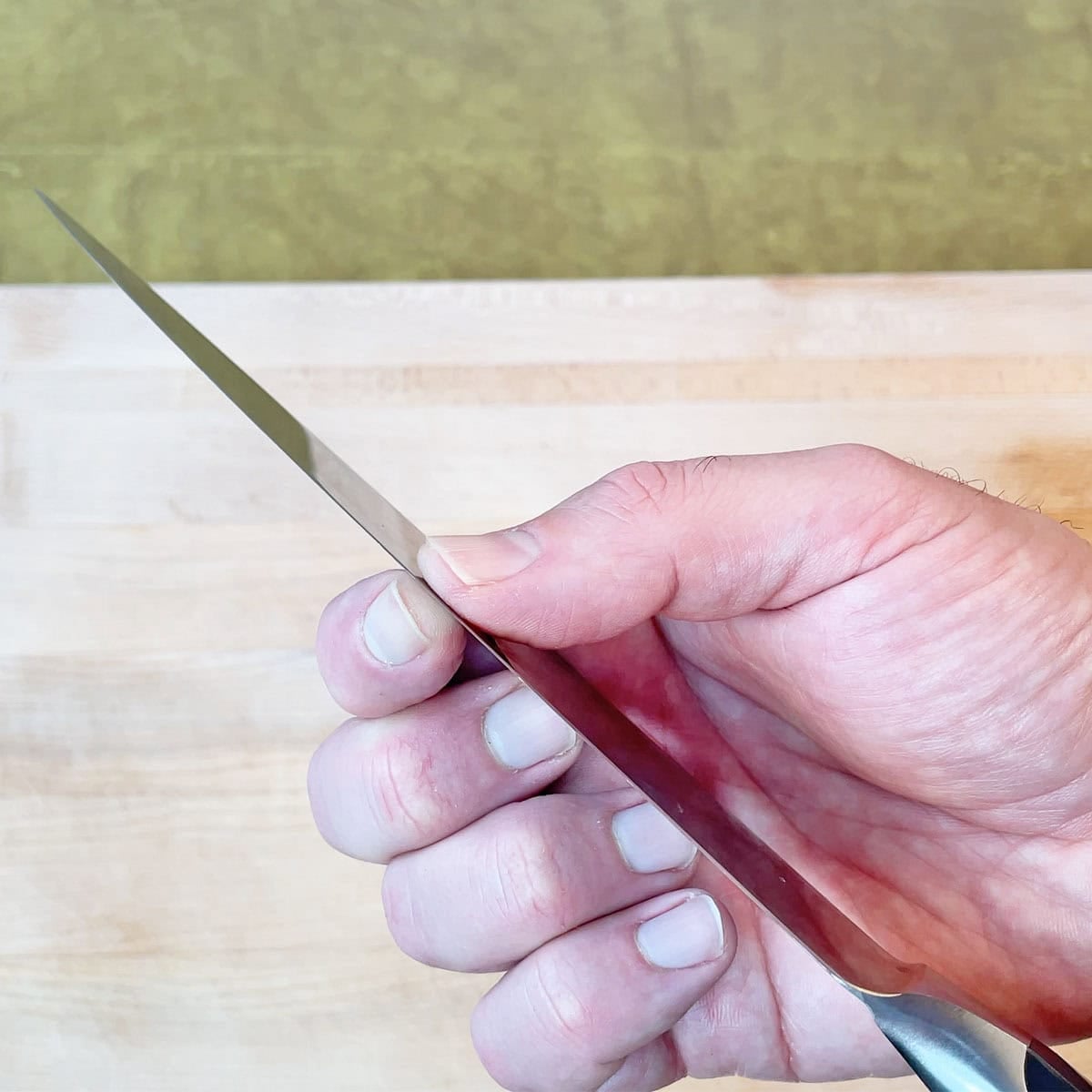 Pinching a knife blade to see how thin it is behind the edge