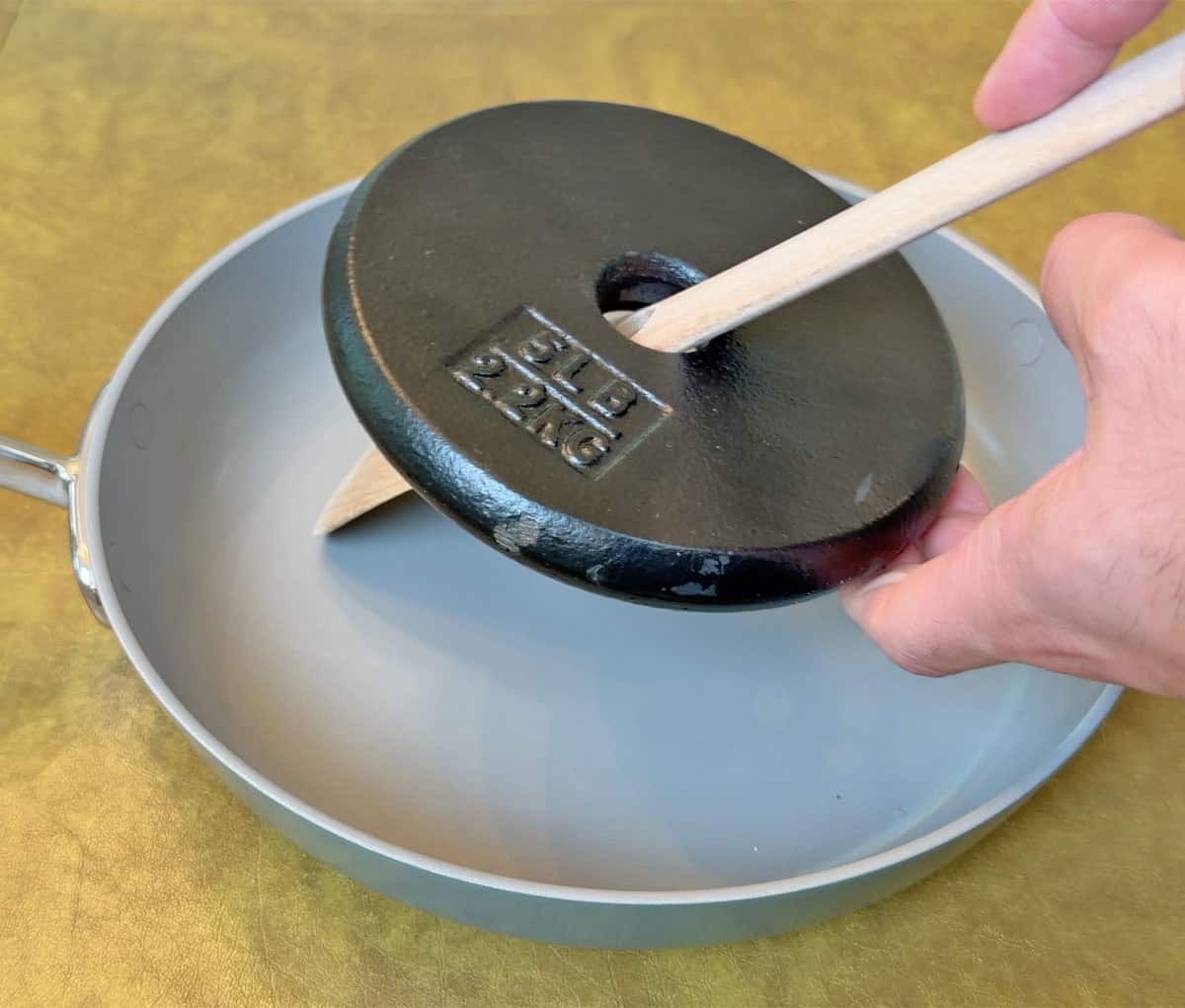Scraping Ninja NeverQuit pan with a weighted wood spatula