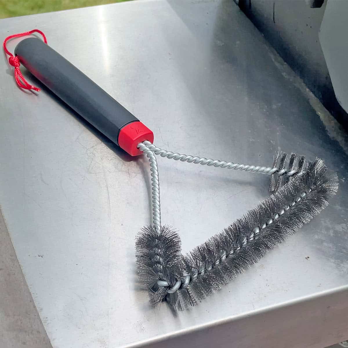 Weber 12 inch three-sided grill brush on a grill